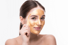 A woman wearing a golden peel mask on her face.